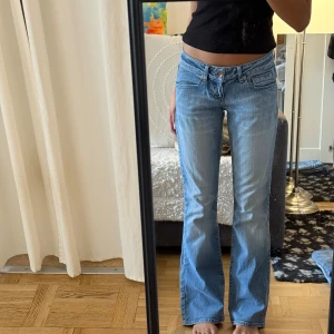 Ljusblå bootcut jeans med broderi - Säljer ett par ljusblå bootcut jeans från LTB med låg midja. Jeansen har snyggt broderi i blått och orange på bakfickorna och klassisk femficksdesign. Perfekta för dig som gillar en avslappnad och trendig look.