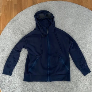 Marinblå Goggle-hoodie från C.P. Company - Hej,säljer min c.p.company tröja eftersom den är för liten.Finns inga defekter på den.Pris kan diskuteras!