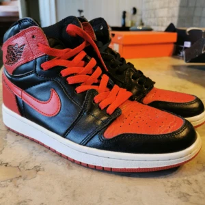 Nike Air Jordan 1 mid - Säljer ett par ikoniska Nike Air Jordan 1 mids  i svart och rött skinn. Klassisk siluett med röda och svarta paneler, röda snören och svarta , vit mellansula. Perfekta för dig som vill sticka ut med en tidlös sneakerlegend.