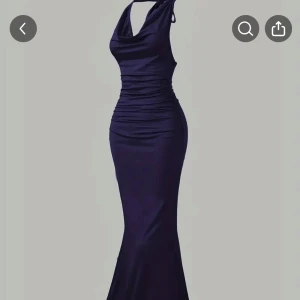 Mörkblå långklänning med knyt - Supersnygg mörkblå långklänning med figurnära passform och draperad halsringning. Klänningen har knyt i nacken och är ärmlös, vilket ger en elegant och stilren look.