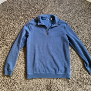 Half zip  Polo Ralph Lauren - Blå långärmad tröja från Polo Ralph Lauren, sparsamt använd. Dragkedjan har en läderdetalj, strl L men lite mindre i storleken.
