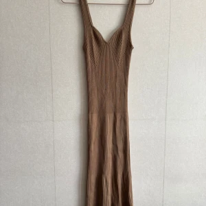 Ribbad långklänning från Gina Tricot - Snygg ribbad långklänning i beige från Gina Tricot. Klänningen har breda axelband, v-ringad urringning och är figurnära med stretchigt stickat material. Perfekt för dig som gillar en enkel men trendig look.