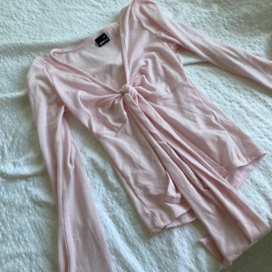 Ljusrosa knytblus  från Gina Tricot - Supersöt ljusrosa omlottopp från Gina Tricot med långa ärmar och snygg knytning framtill. 