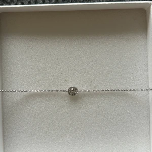 Silverarmband med glittrig cirkel - Ett tunt och stilrent armband i silverfärg med en liten rund dekoration i mitten, täckt av glittrande stenar.