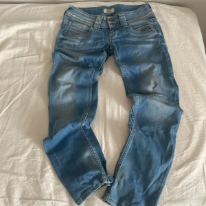 Pepe ljusblå jeans - Snygga ljusblå jeans från pepe med slitna detaljer och klassisk femficksdesign. Jeansen har normal passform, straight ben och dubbla knappar i midjan. Perfekta för dig som gillar en avslappnad men trendig look.