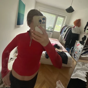 Röd croppad tröja med half zip - Säljer en röd långärmad croppad tröja med half zip och rund dragkedja framtill. Tröjan har en tight passform och är perfekt för dig som gillar en sportig och trendig stil. Enkel att matcha med både jeans och kjol.