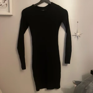 Svart långärmad tajt klänning - En svart, tight och ribbad klänning från FB Sister (New Yorker) i storlek XS. Klänningen är långärmad och har en kroppsnära passform med rund hals. Använd en gång!