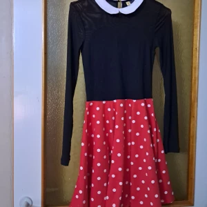 Minnie mouse halloween klänning - Supersöt klänning med svart långärmad överdel, vit klassisk krage och röd kjol med vita prickar. Kjolen är utsvängd och klänningen har en lekfull, retroinspirerad look. Perfekt för dig som gillar färg och mönster! Den är oanvänd.