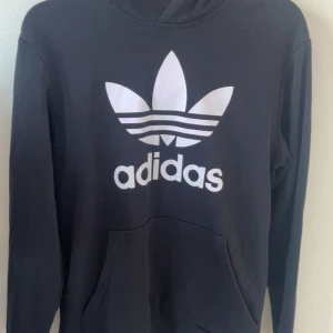 Svart Adidas hoodie med stor logga - Svart hoodie från Adidas i storlek 15-16 motsvarar ca en s. 