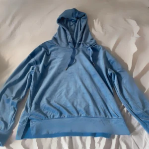 Ljusblå hoodie med huva - Säljer en ljusblå hoodie med huva och snörning. Tröjan har långa ärmar och bred mudd nertill. Perfekt för chill dagar eller när du vill ha en avslappnad stil.