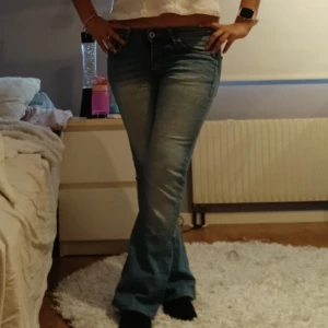 Lågmidjade bootcut jeans - Snygga blå jeans med bootcut. Köpta från H&M och finns inte att köpa längre då de är vintage. En liten fläck på jeansen som inte försvinner i tvätt, därav priset. Går att se på sista bilden, går säkert bort om man försöker. Står ingen storlek men passar som en 34