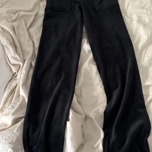 Svarta mjukisbyxor Juicy Couture XS - Svarta mjukisbyxor från Juicy Couture i supermjuk velour. Klassisk rak passform med resår i midjan och två fickor framtill. Använt 2-6 ggr. 