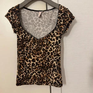 Leopardmönstrad croppad topp - Snygg croppad topp med leopardmönster och djup v-ringning. Toppen har korta ärmar och figurnära passform, perfekt att styla med jeans eller kjol. Materialet är mjukt och stretchigt för en bekväm känsla.