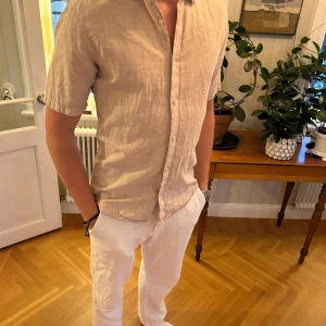Beige linneskjorta med kort ärm - Snygg beige skjorta i linne med korta ärmar. Skjortan är från Only&Sons och är storlek M. Modell är 183cm & 75kg. Bara att skriva om ni undrar något! 