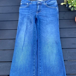 Blå jeans med raka ben från 157 - Snygga blå jeans från 157 i storlek M med kortare benlängd. Jeansen har klassisk femficksdesign, raka ben och normal  Materialet är klassisk denim i bomull. Jenssen har en medel/ låg midja men en fin blå skiftande färg. 