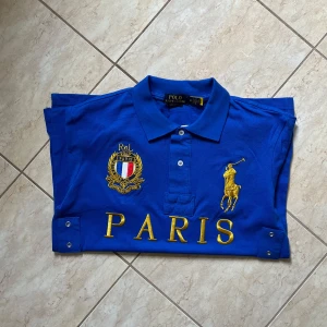 Chief keef polo Paris - Blå pikétröja från Polo Ralph Lauren med broderad gul logga, Paris-text och emblem på bröstet. Nummer 5 på ärm och rygg. Klassisk krage med knappar och korta ärmar. Tillverkad i bomull, perfekt för en sportig och stilren look. Säljes pga inte riktigt min stil och bara låg i garderoben. Pris kan diskuteras vid snabbaffär.