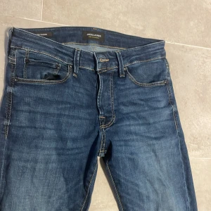 jeans från Jack & Jones - Snygga blå slim fit jeans från Jack & Jones, modell Glenn.kontrastsömmar och normalhög midja. Jeansen är i stretchigt denim för en bekväm passform och stiliga nästan som nya!                          hör av dig vid frågor eller mer bilder!!