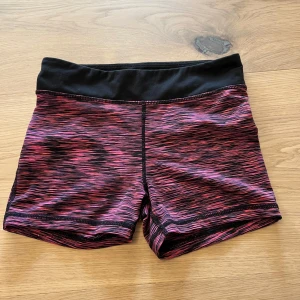 Träningsshorts H&M Sport rosa/svart - Snygga träningsshorts från H&M Sport i tight passform. De har ett svart midjeband och ett mönster i rosa, lila och svart. Perfekta för gymmet eller löprundan, stretchigt material som sitter skönt på kroppen.