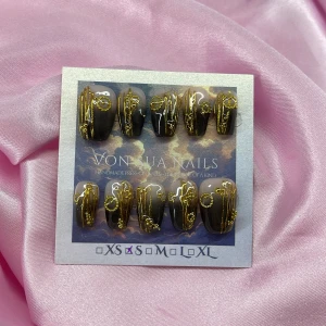 Onyx (S);Short Coffin - Handgjorda press-on naglar i svart och nude med lyxiga 3D-detaljer i guld. Naglarna har en elegant, coffin form och dekoreras med glittrande, upphöjda mönster. Perfekt för dig som vill ha en unik och konstnärlig look på naglarna. I storlek S: 15 mm, 11,5 mm, 12 mm, 11 mm, 9 mm 