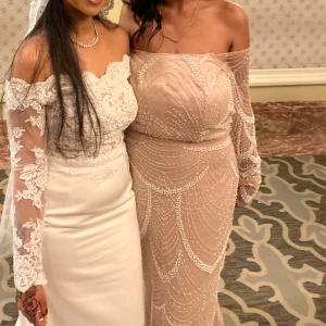 Champagnefärgad långklänning med pärlor - Superfin långklänning i champagnefärg med offshoulder och långa ärmar. Klänningen är täckt av glittriga pärlor i mönster och har en figurnära passform. Perfekt för bal eller fest! Klänningen är skräddarsydd i Egypten!
