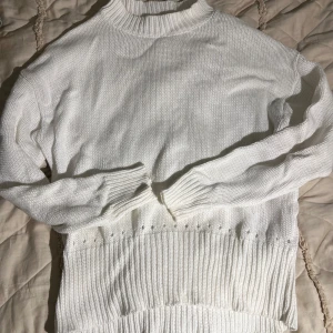 Vit stickad tröja - Vit stickad tröja med ribbad hög krage och bred ribbstickad nederkant. Tröjan har långärmad design och är perfekt för lager-på-lager under kyliga dagar. Enkel och stilren look som passar till det mesta.