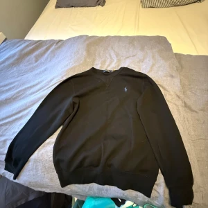 Ralph Lauren sweatshirt  - Klassisk svart sweatshirt från Polo Ralph Lauren med rund halsringning och broderad logga på bröstet. Tröjan har långa ärmar och ribbade muddar vid ärmslut och nederkant. Perfekt för en stilren och avslappnad look.