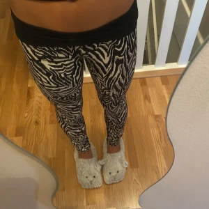 Zebramönstrade leggings i svart och vitt - Säljer ett par snygga leggings från Stronger med zebramönster i svart och vitt. De är tighta och sitter skönt på kroppen, perfekta för dig som vill sticka ut lite extra. Materialet är stretchigt och mjukt, vilket gör dem riktigt bekväma att ha på sig hela dagen. Man kan även vika ner i midjan vilket jag gjort på den här bilden 