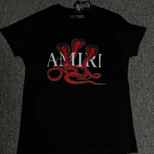 Svart Amiri t-shirt med röd orm - Svart t-shirt från Amiri med ett stort tryck av tre röda ormar och vit Amiri-logga på bröstet. Klassisk passform med korta ärmar och rund hals. Grym statement-piece för dig som gillar streetwear och coola prints. Pris kan diskuteras