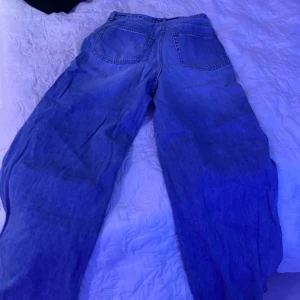 Baggy blå jeans ( kan ta bort bältet ) - Säljer ett par blå jeans med bred passform och snörning i midjan. Byxorna har klassiska bakfickor och är tillverkade i jeansmaterial. Perfekta för dig som gillar en avslappnad och trendig look.
