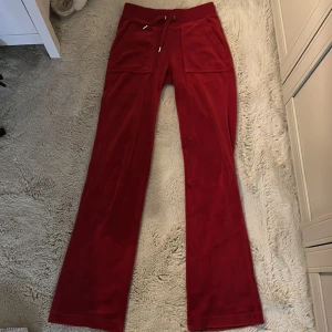 Röda velourbyxor Juicy Couture XXS - Röda velourbyxor från Juicy Couture med bred resår i midjan och snörning. Byxorna har stora fickor fram och bak med knappdetaljer. Klassisk loose passform och raka ben, perfekta för en chill och trendig look.                                                        Använder inte dessa längre. De har blivit för små för mig. Säljer nu dessa 
