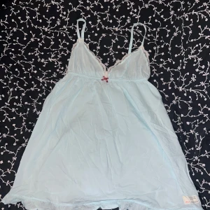 Ljusblå Odd Molly kortklänning - Supersöt ljusblå kortklänning från Odd Molly i 100% bomull. Klänningen har smala axelband, spetsdetaljer vid bysten, liten rosett framtill och volangkant nertill. Broderad Odd Molly-logga på ryggen. Perfekt för en somrig look!