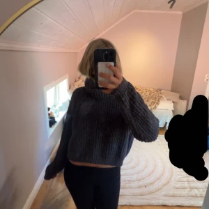 Mörkgrå stickad croppad tröja Ü - Mysig mörkgrå stickad tröja från Ü med croppad passform och bred polokrage. Väldigt skön på vintern/höst