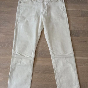 Vita jeansbyxor från H&M Essentials - Snygga vita jeansbyxor från H&M Essentials i regular fit. Raka ben och normal passform. Perfekta för en clean och fräsch look! Essentials jeansen har tillverkats med en lägre miljöpåverkan. 