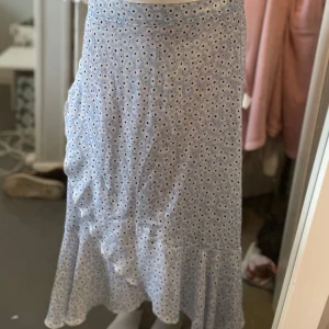 Ljusblå långkjol med volang - Supersöt ljusblå långkjol med små vita blommor och volang nertill. Kjolen har en flowy passform och är perfekt för vår och sommar. Fint skick! 