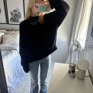 Svart tjock stickad tröja - Mysig svart tjock stickad tröja med lite högre hals. Har ett hål vid armen men som man inte märker av  