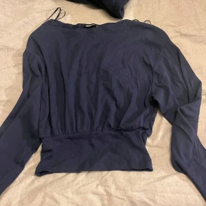 Mörkblå långärmad topp Gina Tricot - Säljer en mörkblå långärmad topp från Gina Tricot i storlek XS. Modellen är ribbad med bred midjeresår som ger en snygg passform. Perfekt till jeans eller kjol för en stilren look. Materialet är mjukt och stretchigt för extra komfort.