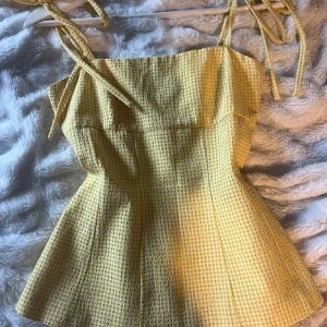 Zara topp - Superfin gul linnetopp med rutigt mönster och smala axelband som knyts upptill. Toppen har en lätt utsvängd form och är perfekt för varma dagar. Materialet känns luftigt och toppen har en söt vintagekänsla.
