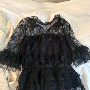 Svart spetsklänning från Bubbleroom - Supersnygg svart spets blus från Bubbleroom med volangdetaljer och transparenta ärmar. 