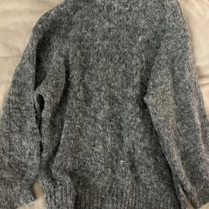 Grå stickad tröja från Gina Tricot - Mysig grå stickad tröja från Gina Tricot i storlek S. Tröjan har en oversized passform, lång ärm och rund halsringning. Perfekt för lager-på-lager och chill dagar. Materialet är fluffigt och ger en cool, avslappnad vibe.