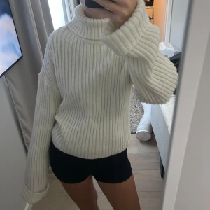Vit ribbad polotröja med oversized ärmar - Säljer en supermysig vit polotröja med bred ribbstickning och oversized ärmar. Tröjan har hög polokrage och är perfekt för kalla dagar. Den är stickad och har en loose fit.