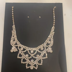 Glittrigt halsband med strass - Elegant halsband med glittrande strassdetaljer i ett intrikat mönster. Perfekt för att ge en lyxig touch till din outfit. Kedjan är justerbar för bästa passform.