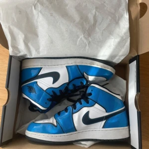 Nike Air Jordans i blått och vitt - Nike Air Jordans 1 storlek 39/6.5 Signal blue/Black-White. Använda ca 3 ggr, väldigt fint skick, några creasing på tån men inte mycket.  Nypris: mellan 3000 - 4000kr