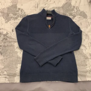 Mörkblå stickad tröja från Pier One  - Säljer en snygg mörkblå stickad tröja från Pier One  med dragkedja vid halsen. Tröjan har ett diskret mönster upptill och långa ärmar. Finns inga slitage eller nåt sånt från tröjan använd endast ett fåtal gånger sedan har den bara legat i min garderob. Om du har några funderingar kring tröjan   så bara fråga svarar så snabbt som det bara går 