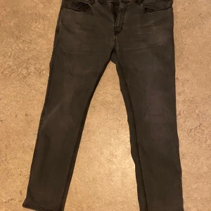 Svarta Gråa Hugo Boss jeans - Snygga svarta Hugo Boss jeans  med en klassisk femficksdesign. De har en rak passform och är perfekta för en stilren look. Byxorna har en knapp och dragkedja framtill.