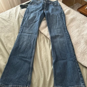 Blå jeansbyxor - Snygga blå jeansbyxor med en klassisk design. De har en normal passform och är perfekta för en avslappnad stil. Byxorna har en knapp och dragkedja framtill och är utsvängda nertill. 