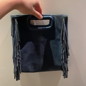 Blå maje mockaväska med fransar - Snygg blå väska i mocka med fransar på sidorna och ett praktiskt handtag. Den har en avtagbar axelrem för extra flexibilitet. Liten sannolikhet att jag accepterar lägre pris då jag sänkt så långt det gått!🩷