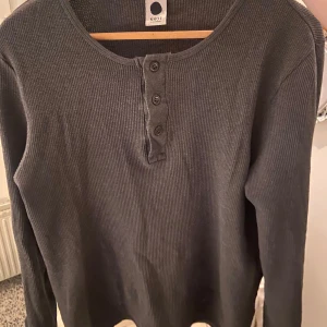 Grå ribbad Henley Shirt från NN07 - Säljer denna grymma tröja från NN07 då den tyvärr blivit för liten. Använd ytterst fåtal gånger så jättebra skick. Sitter som en liten M / stor S. Bara att skriva vid minsta fråga eller för fler bilder! 