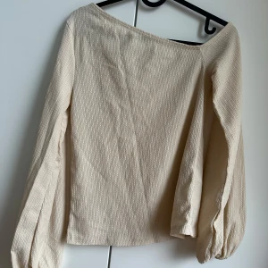 Offshoulder  - Blus med offshoulder på ena axeln och ballongärmar.