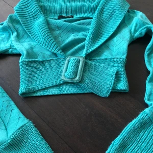 Turkos stickad bolerotopp från Jane Norman - Snygg turkos stickad bolerotopp från Jane Norman med ett brett ribbat bälte och krage. Superfint över ett linne, går att öppna upp den också 🥰osäker över storleken men skulle gissa på S!