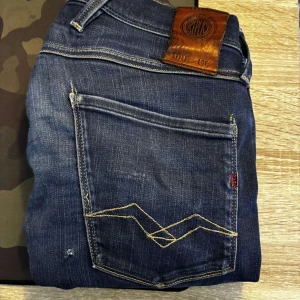 Blå jeans från Replay - Säljer ett snygg och skön replay jeans, det har ett hål och uppsydd som man inte lägger märke!